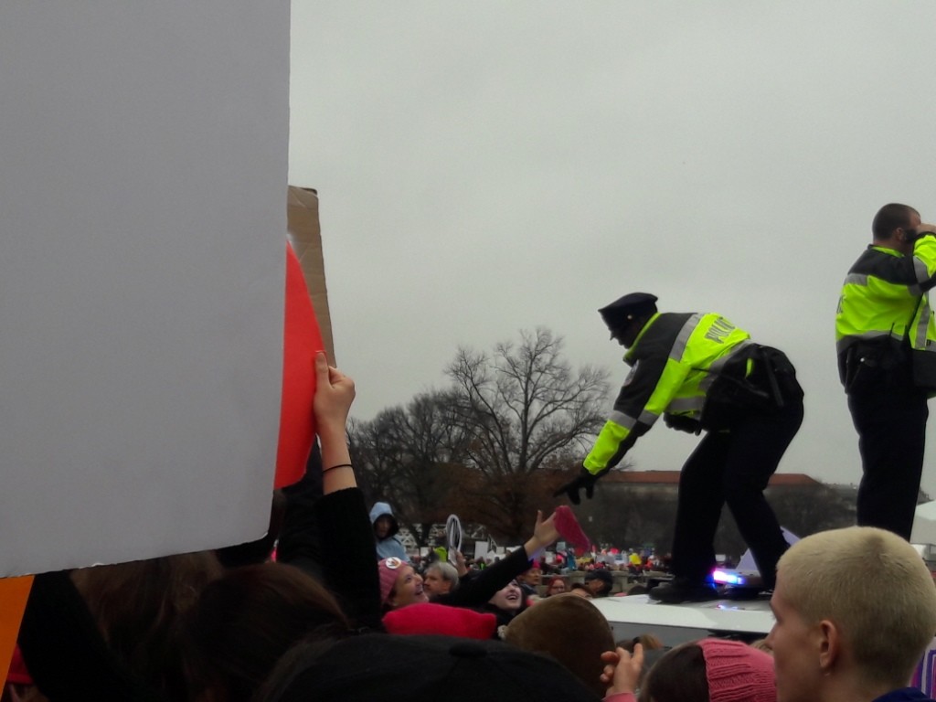 Полицейские берут розовую шапку - символ протеста - у демонстрантов, в знак их поддержки